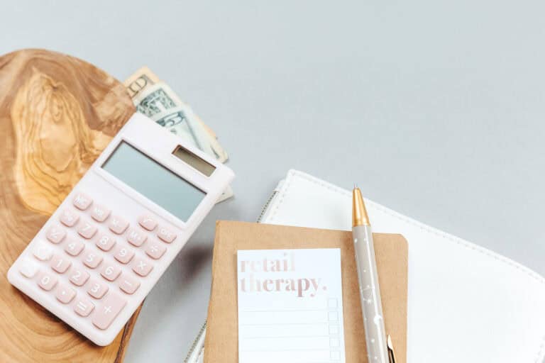retail-therapy-notepad-pen-money-dollars-calculator-wood-grey-background